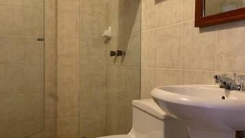 Un baño con inodoro, lavamanos y zona de ducha.