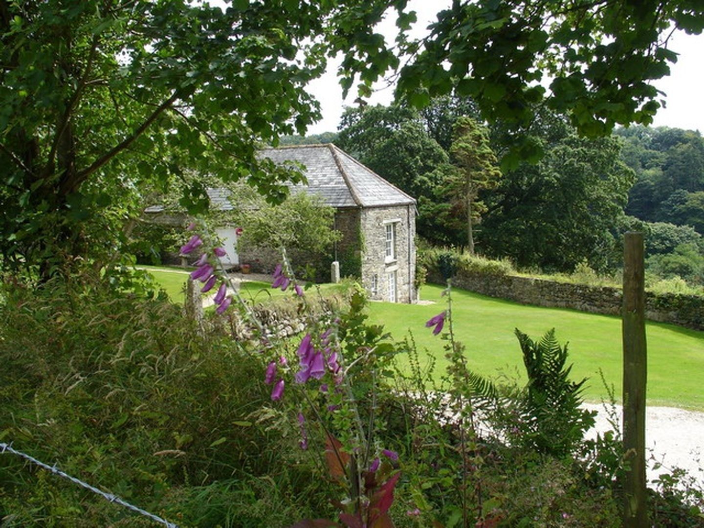 Un bâtiment en pierre doté d’un toit en pente, entouré d’une pelouse bien entretenue et d’une végétation luxuriante.