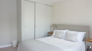 A bedroom with a bed, a nightstand, a lamp, and a wardrobe. - Flat 8 Seascape (Newquay)