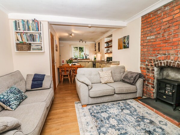 A cozy living room with two grey sofas, a patterned rug, and a brick fireplace.