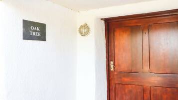 Une porte en bois avec une poignée en laiton, un heurtoir en laiton et une enseigne portant l’inscription « CHÊNE » sur le mur.