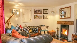 A cozy living room with a leather sofa, a fireplace, and a dining area. - 11 The Green (Budleigh Salterton)