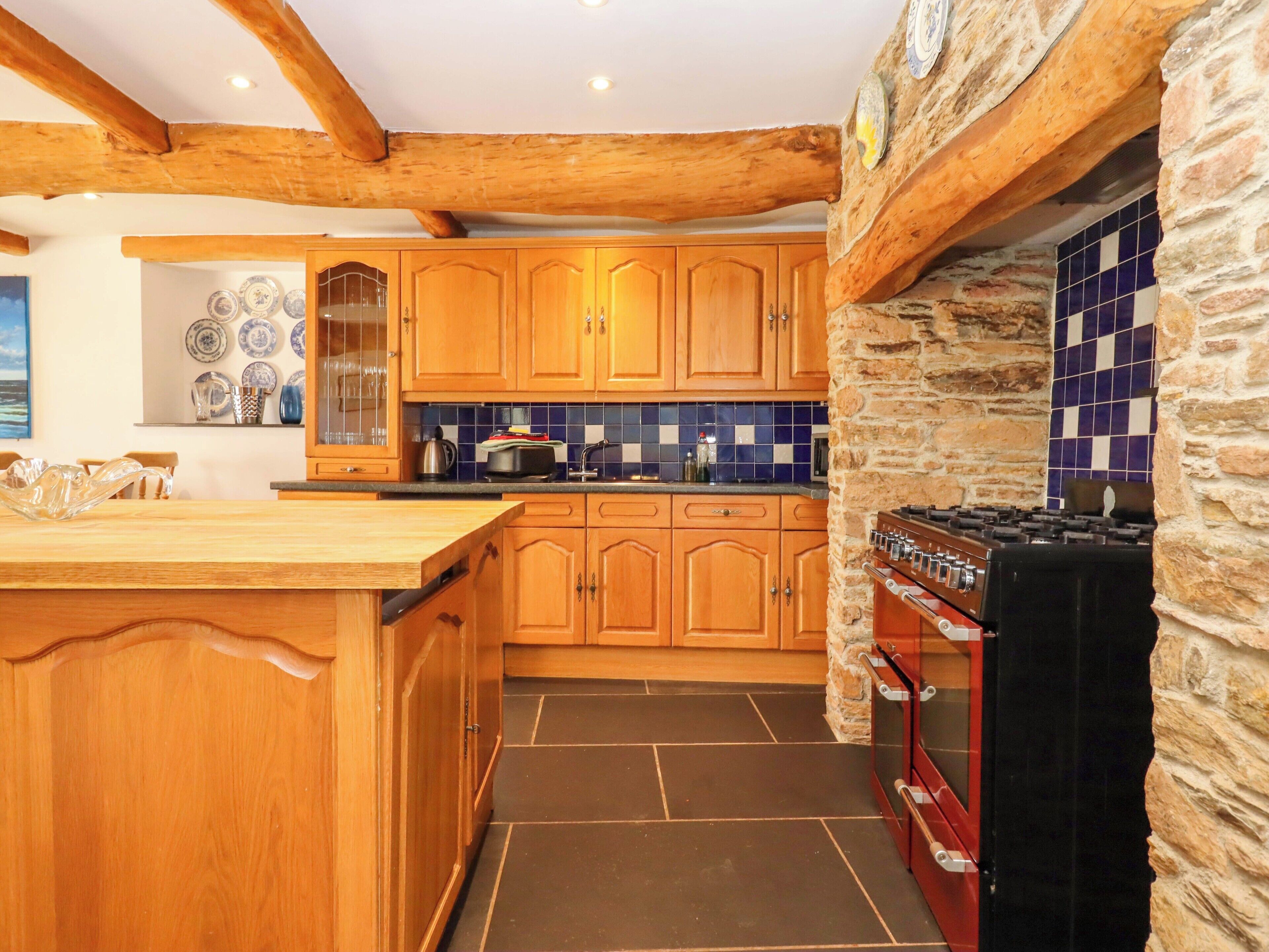 A kitchen with wooden cabinets, a stone wall, and a tiled backsplash.