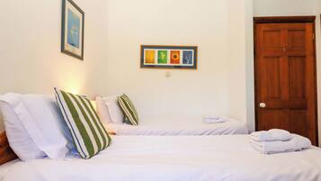 A hotel room with two beds, a wooden door, and a framed picture on the wall.