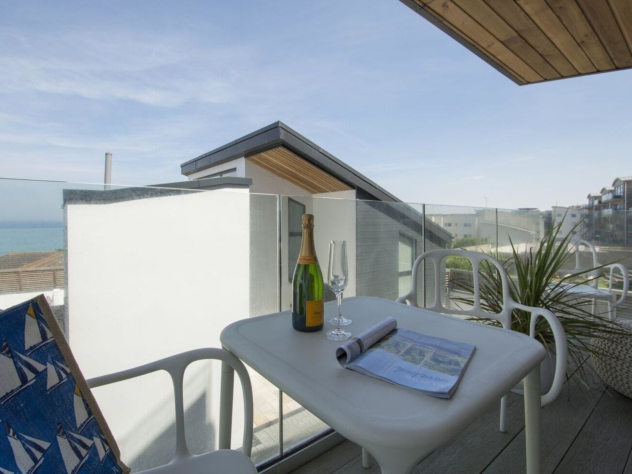 Ein Balkon mit Tisch, einer Weinflasche und einem Glas.