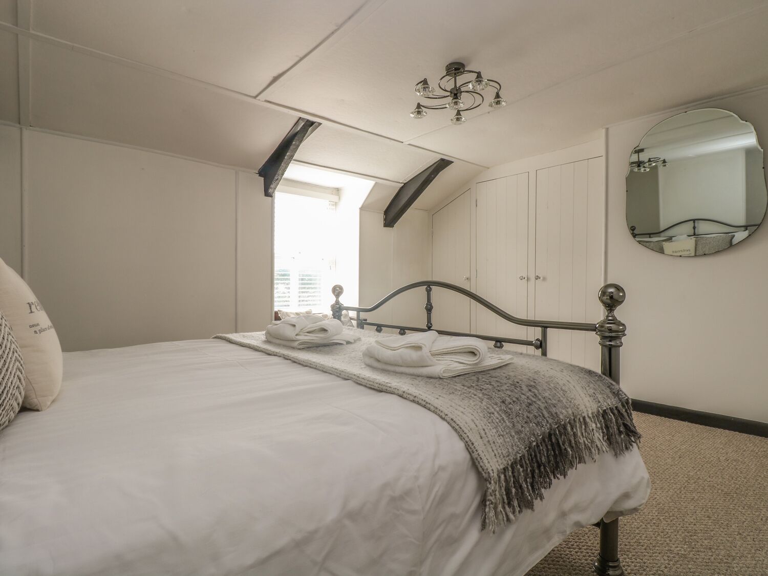 Un dormitorio con una cama, un espejo y una ventana.