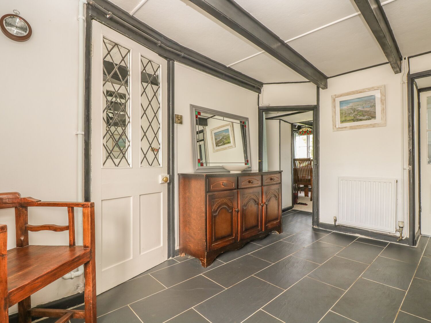 A hallway with a wooden bench, a mirrored cabinet, and a radiator.