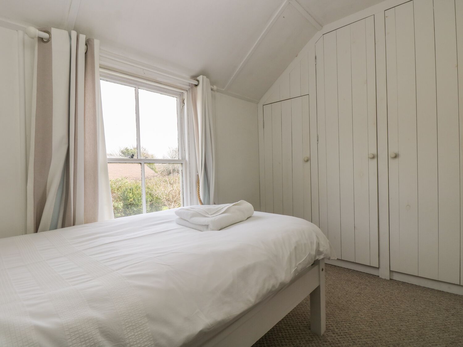 Ein Schlafzimmer mit Bett, Fenster und Kleiderschrank.