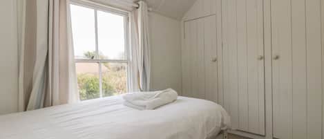 Ein Schlafzimmer mit Bett, Fenster und Kleiderschrank.