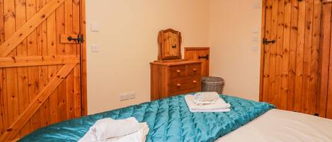 A bedroom with a bed, wooden wardrobe, and a dresser.