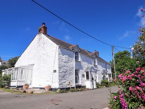 A white cottage with a stone facade, a visible chimney, and a sign indicating it is a bed and breakfast. - Agar Cottage (Port Isaac)