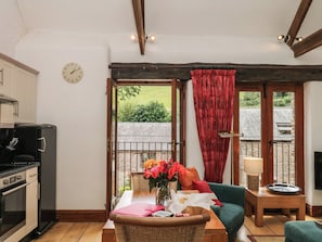 A cozy room with a dining table, a sofa, a kitchen area, and a view of the outdoors.
