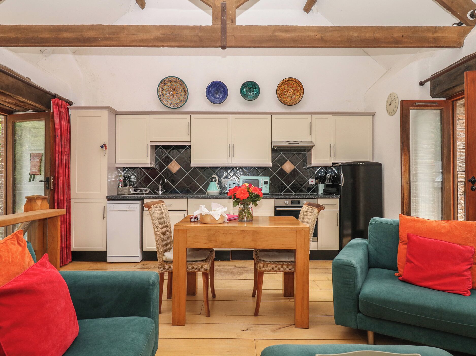 A cozy living room with a dining table, chairs, and a sofa.