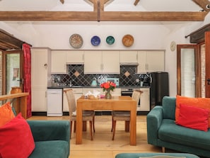 A cozy living room with a dining table, chairs, and a sofa.