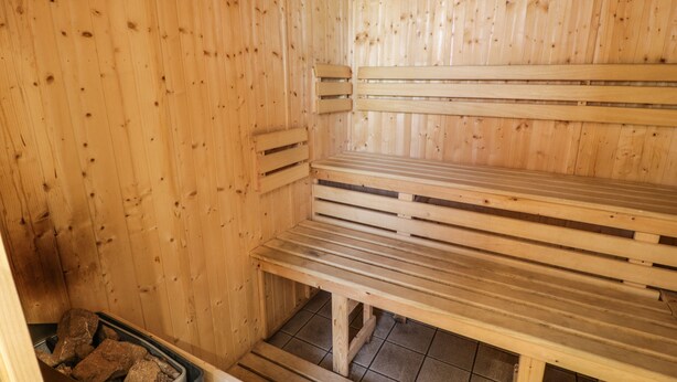 Un sauna en bois, doté de bancs et d’un bassin en pierre.