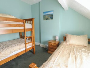 A room with bunk beds, a bedside table with a lamp, a small drawer, and a nightstand with a lamp. - Halford Hill (Caernarfon)
