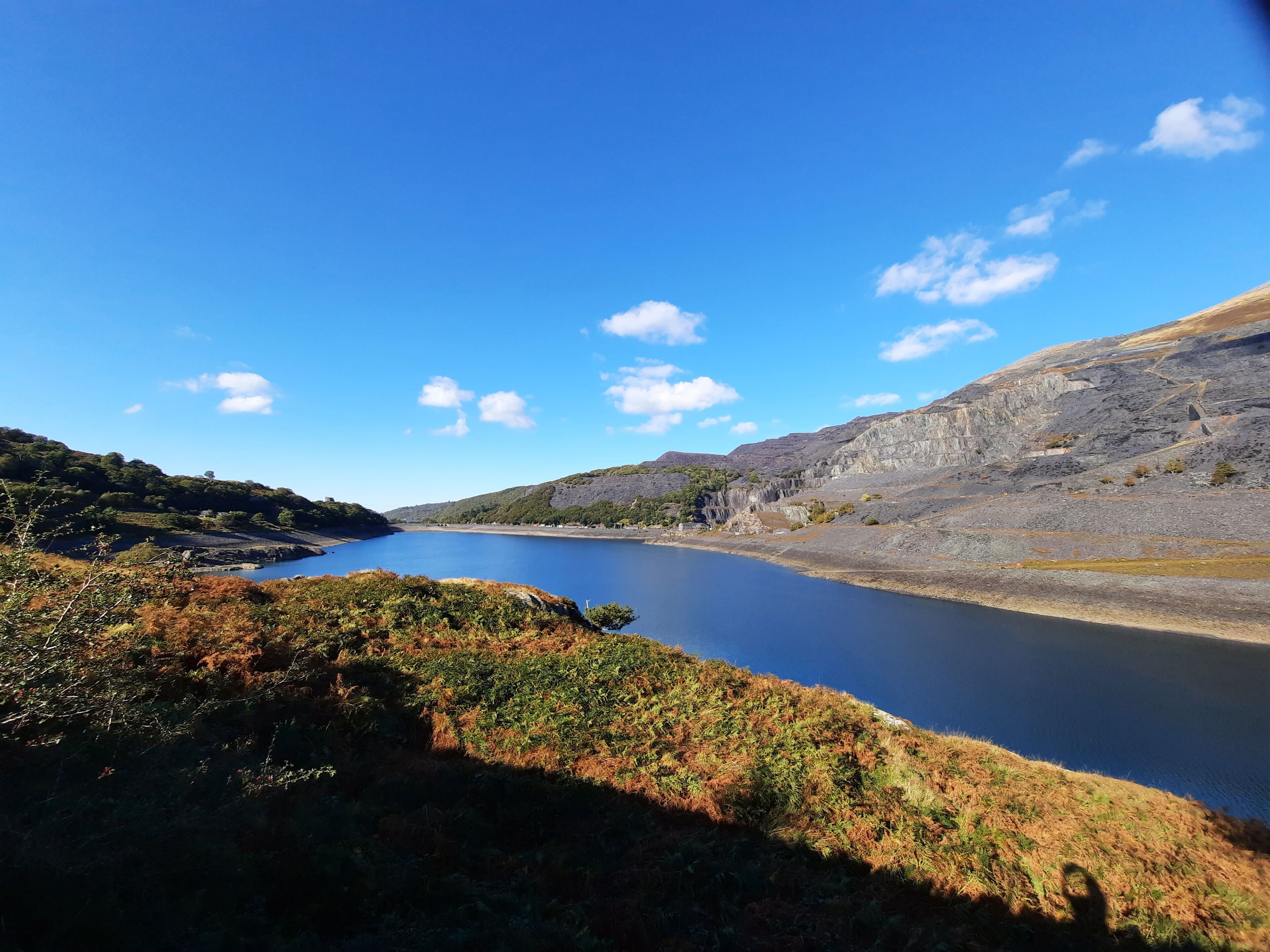 Un paisaje natural con un lago, colinas y vegetación escasa.