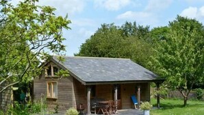 A small wooden cabin with a porch, a dining table, and chairs. - The Springs (Ryde)