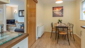Une cuisine moderne avec des meubles en bois, une table à manger avec des chaises, un téléviseur et une cheminée.