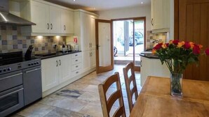 A modern kitchen with white cabinets, a stove, and a dining area with a wooden table and chairs.