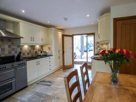 A modern kitchen with white cabinets, a stove, and a dining area with a wooden table and chairs.