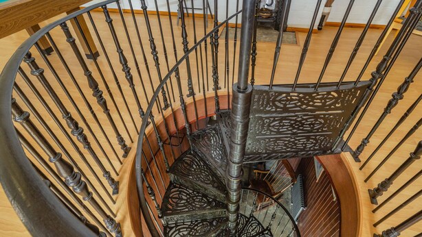 A spiral staircase with ornate metal railings and wooden steps. - Southport Coach House (Southport)