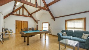A spacious room with a pool table, a sofa, and a high ceiling with exposed wooden beams. - Southport Coach House (Southport)
