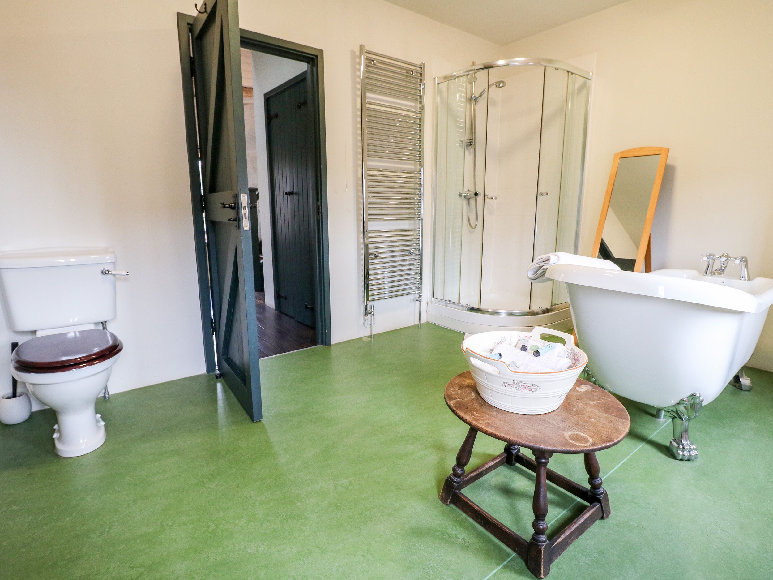 A bathroom with a toilet, a bathtub, a shower, and a small table with a basket.