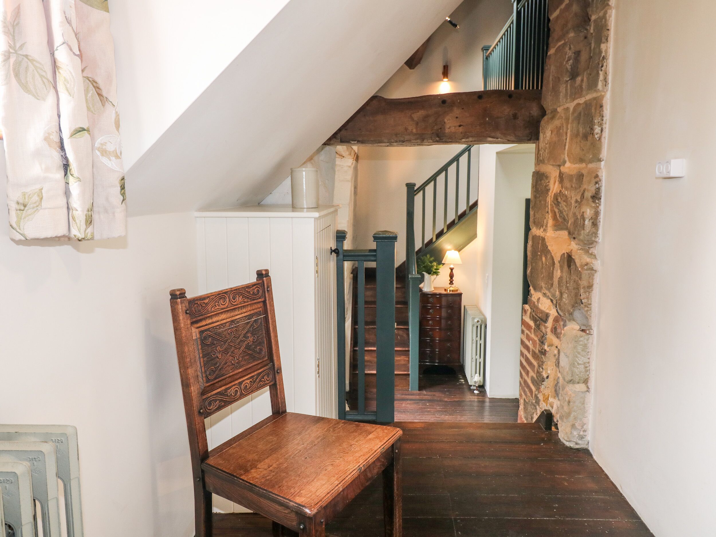 Ein Holzsessel in einer Diele mit einer Treppe zu einem Raum mit einer Steinwand.