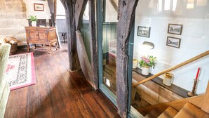 A rustic interior with exposed wooden beams, a wooden staircase, and a view of a stone wall. - Porter's Lodge (Tamworth)