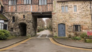 A traditional stone building with a timber-framed structure, a stone archway entrance, and a blue door. - Porter's Lodge (Tamworth)