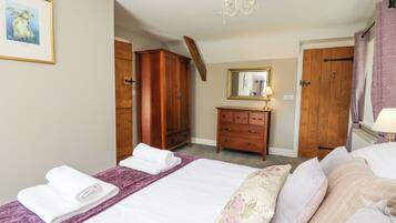 A bedroom with a bed, a dresser, a mirror, and a chandelier.
