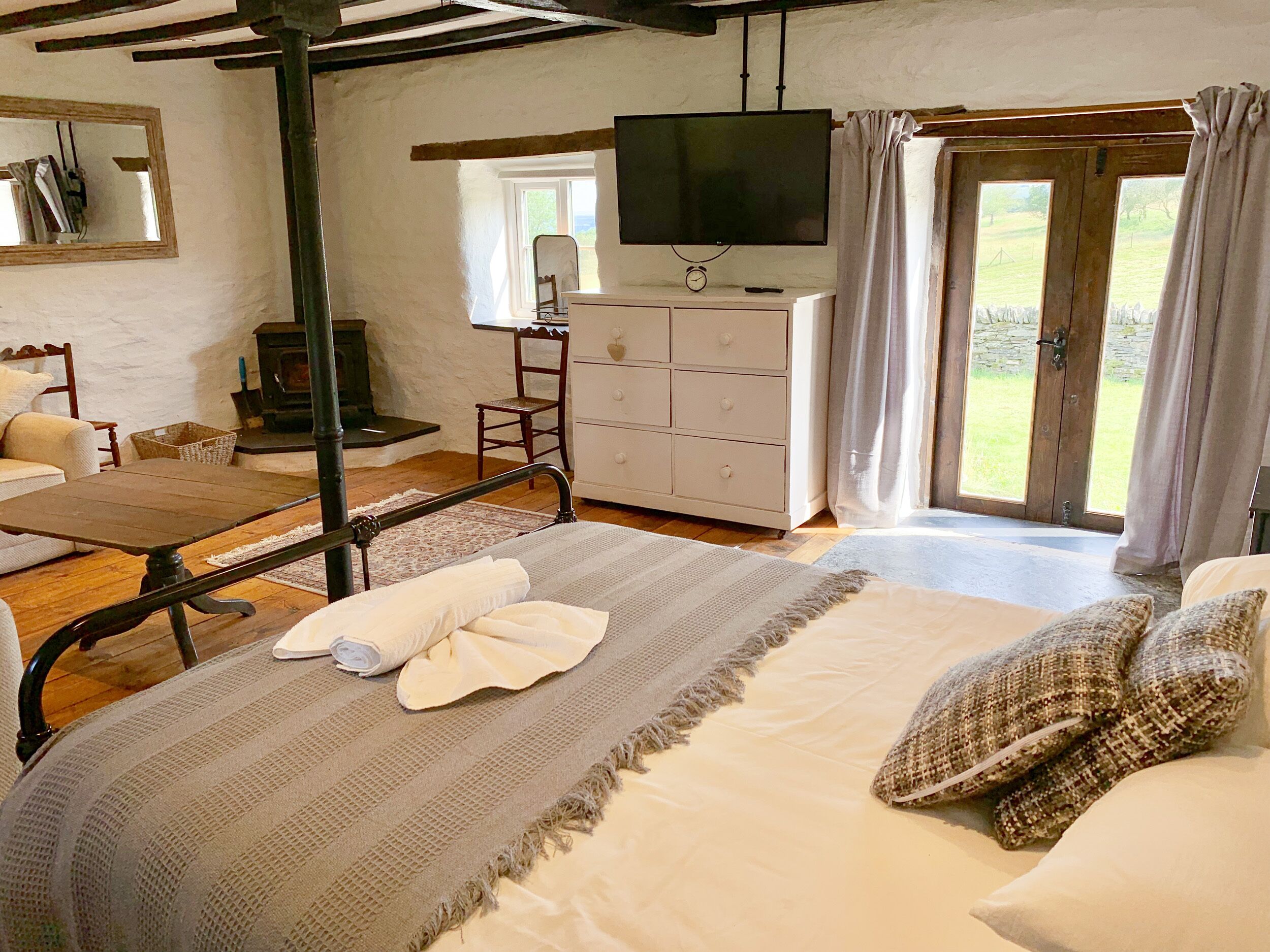 A bedroom with a bed, a dresser, a television, and a window with curtains.