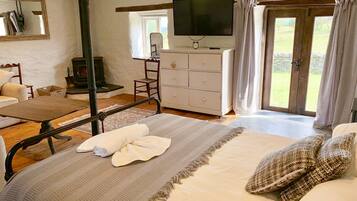 A bedroom with a bed, a dresser, a television, and a window with curtains.
