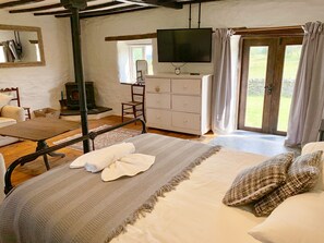 Un dormitorio con cama, cómoda, televisor y ventana con cortinas.