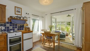 Eine Küche mit Holzausstattung, einem Herd und einem Essbereich mit Tisch und Stühlen.