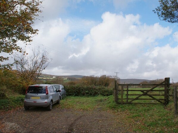 A car parked on a rural road with a wooden gate and a fence in the background. - The Annexe, Higher Lydgate Farmhouse (Postbridge)