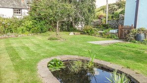 Un jardin bien entretenu, agrémenté d’un bassin, de bordures en pierre et d’une grande variété de plantes.