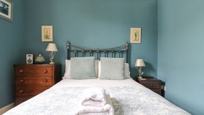 Une chambre à coucher comprenant un lit, deux tables de chevet, une commode et deux lampes fixées au mur.