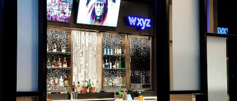Un bar con un letrero de neón que dice "WXYZ" y una pantalla de televisión mostrando una imagen colorida.