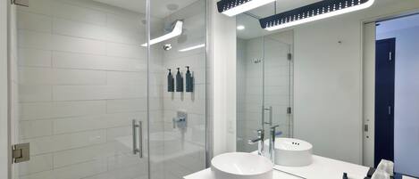 Une salle de bain moderne avec une douche à parois de verre, un lavabo blanc et un grand miroir.