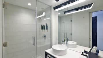 A modern bathroom with a glass-enclosed shower, a white sink, and a large mirror.
