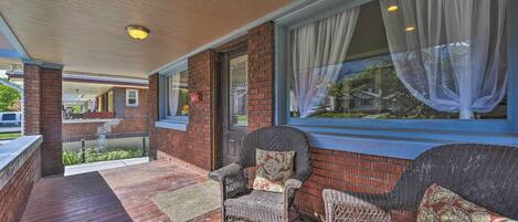A covered porch with wicker furniture and a brick wall.