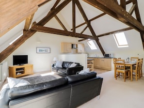 Relax in this cozy attic room with a high ceiling, leather sofa, and flat-screen TV.