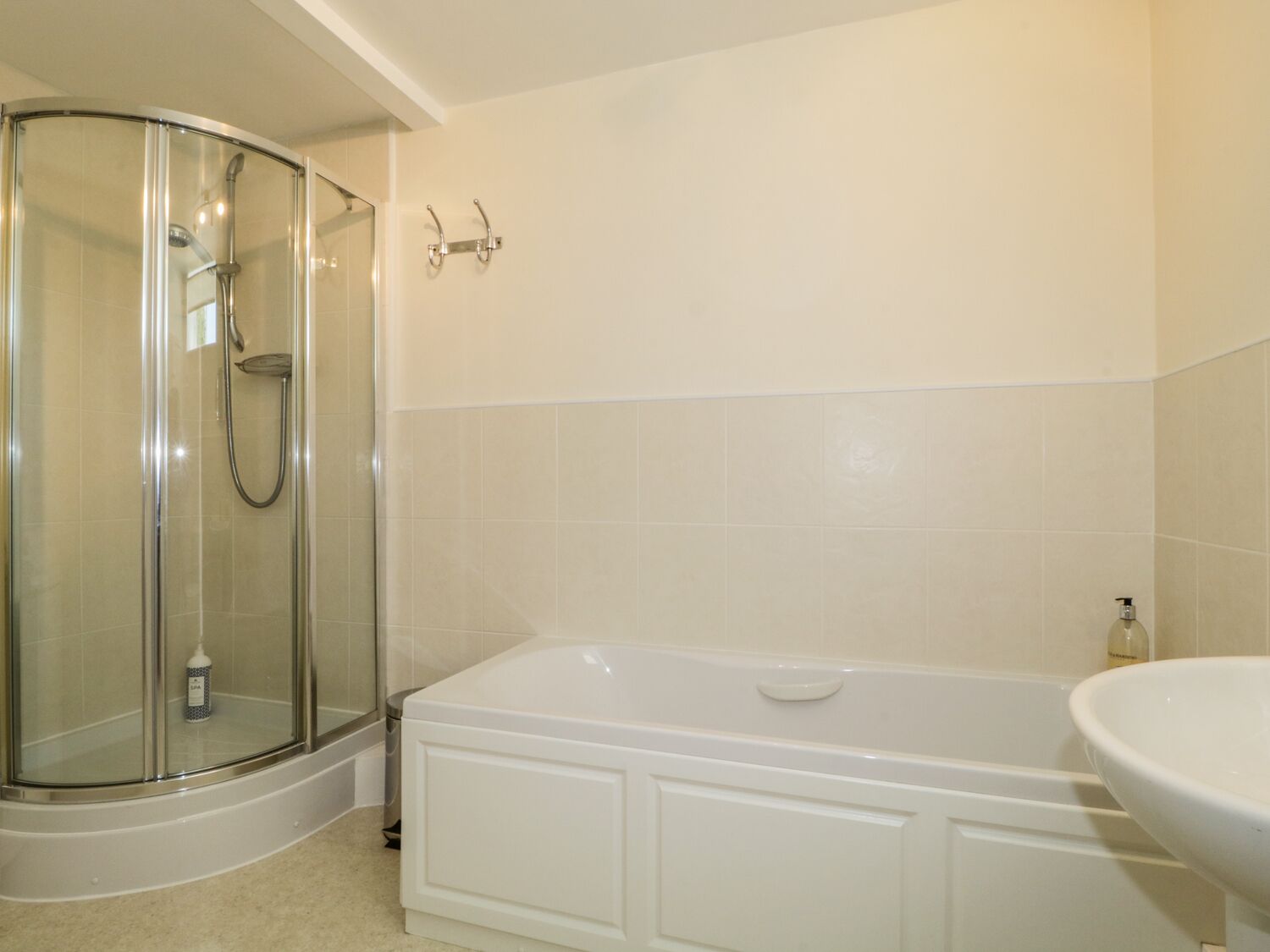 A bathroom with a glass-enclosed shower, a white bathtub, and a sink.