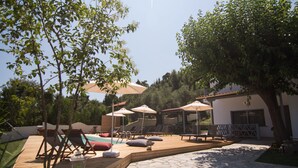 A poolside area with lounge chairs, umbrellas, and a stone deck. - Casa Luxury Suites (Kassandra)