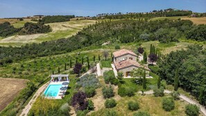 A stone villa with a swimming pool, surrounded by lush greenery and terraced fields.
