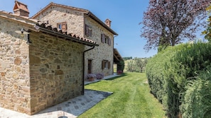 A stone building with a sloped roof, a small porch, and a well-maintained lawn.