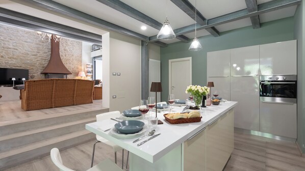 Una cocina moderna con una isla central, muebles blancos y un horno empotrado.