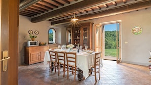 Un comedor con una mesa dispuesta para cuatro personas, sillas de madera, un mostrador tipo bufé y vistas al exterior.